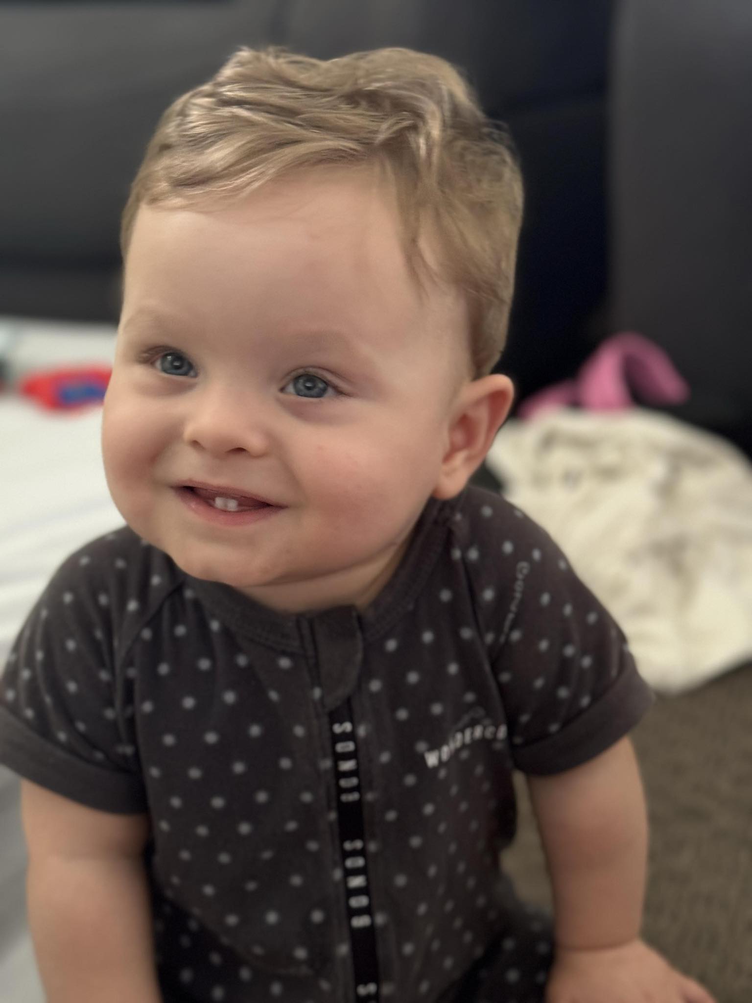 Braedan sits up, a happy toddler.