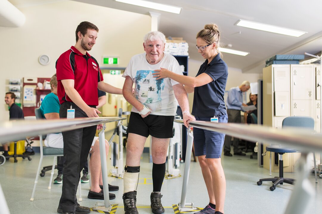 Physiotherapist and student assist patient in rehabilitation