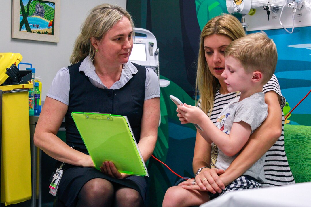 Clinical nurse consultant discussing flu immunisation with mother and her young son