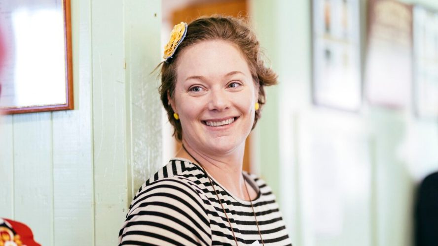 A woman in a black and white striped shirt smiles at the camera