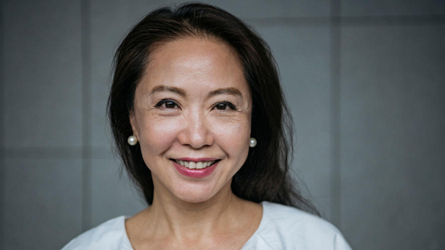 A head and shoulders portrait of a woman. She has dark hair and is smiling at the camera.